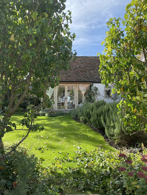 Une maison traditionnelle dotée d’un jardin bien entretenu, d’une pelouse et de diverses plantes.