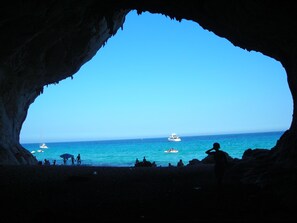 A cave opening to a beach with a clear view of the sea and boats. - MarVy house (Arbatax)