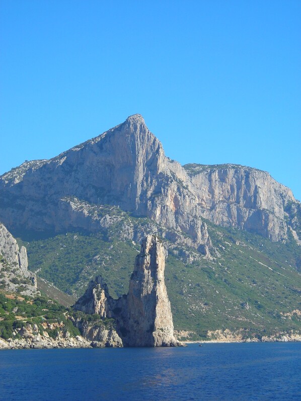 Eine Küstenlandschaft mit einem markanten Felsen im Meer und einem Berg im Hintergrund.