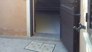 An open door leading to a room with a bed, a ceiling fan, and a wall-mounted shelf. - MarVy house (Arbatax)