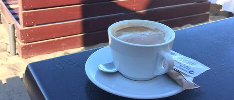 Een kop koffie op een tafel, met uitzicht op het strand.