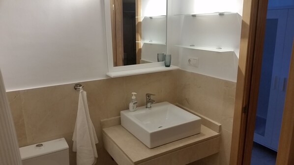 A bathroom with a white sink, a mirror, and a towel rack.