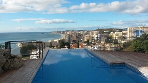 Une piscine offrant une vue sur le paysage urbain côtier, avec ses bâtiments et la mer.