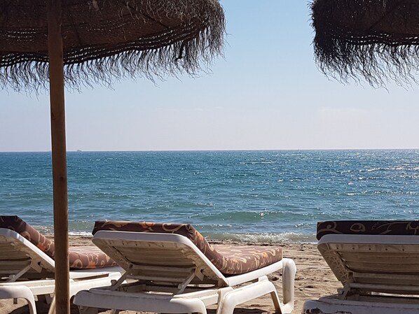 Relax in comfort under a shaded umbrella, surrounded by the soothing sounds of the ocean.