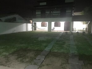 A courtyard with a grassy area, stone pathway, and a building with multiple windows and doors.