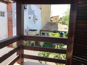 A balcony with a view of neighboring buildings and greenery.