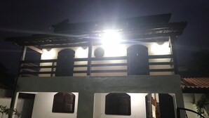 A two-story building with a balcony and a bright light source above it. - Casa De Praia Anequim (Cabo Frio)