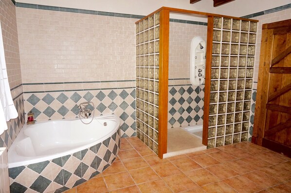 Une salle de bain avec une baignoire, un espace douche et des murs carrelés.