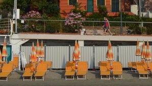 Un edificio con facciata rossa e gialla, un balcone con sedie arancioni e una persona che cammina.