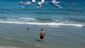 Una spiaggia con persone, una riva sabbiosa e barche nell'acqua.