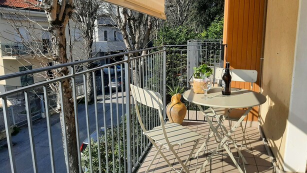 A balcony with a table, chairs, a bottle, and a vase. - Large and bright, a stone's throw from the castle, balcony, FREE WIFI, A / C, parking space (Rimini)