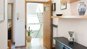 A hallway with a wooden door, a small potted plant, a black cabinet, and a shelf with decorative items. - Large and bright, a stone's throw from the castle, balcony, FREE WIFI, A / C, parking space (Rimini)