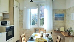A kitchen with a dining table, chairs, a microwave, an oven, and a window with curtains. - Large and bright, a stone's throw from the castle, balcony, FREE WIFI, A / C, parking space (Rimini)