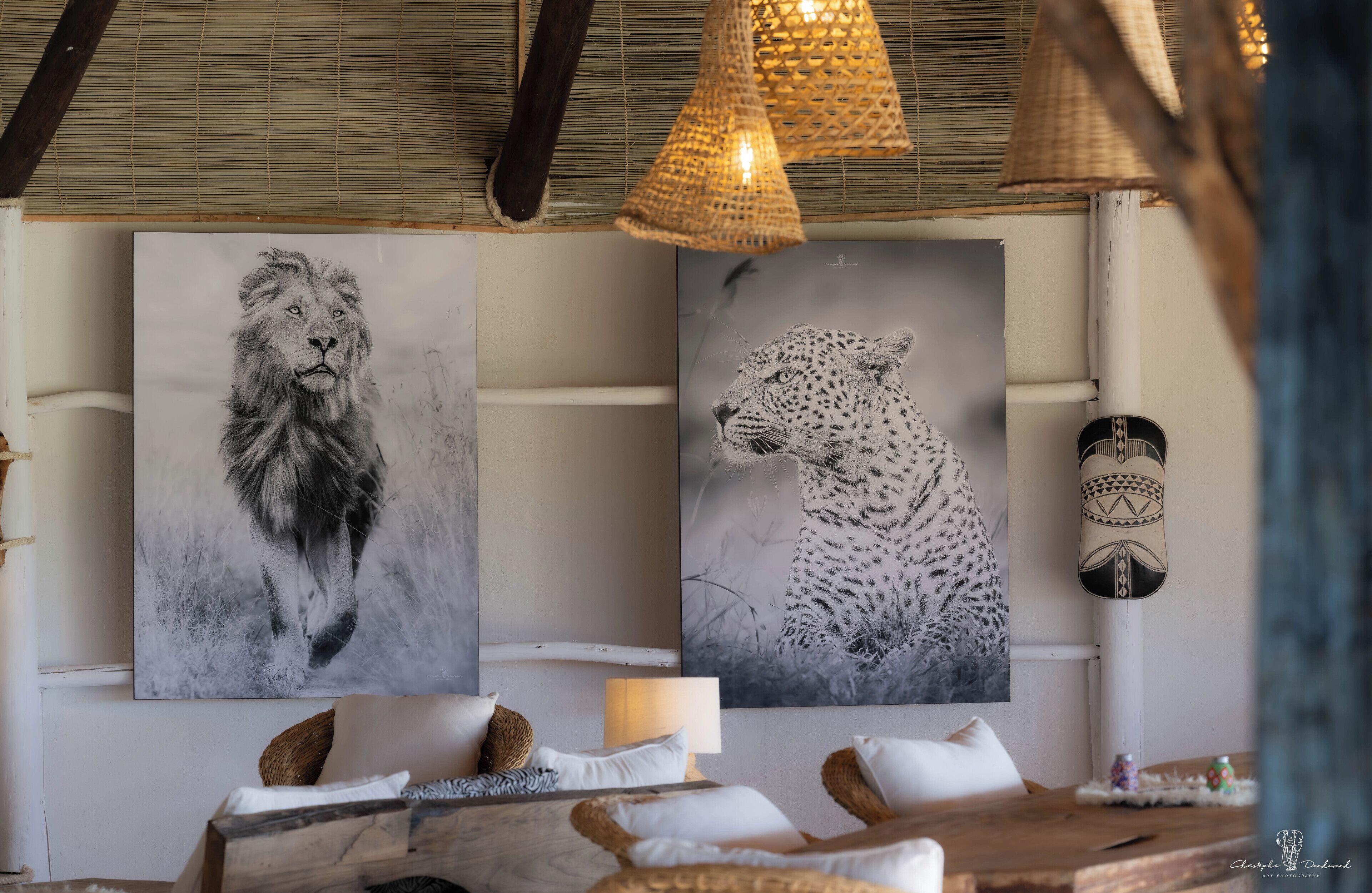 A room with a bed, a wooden table, and two wall-mounted paintings of a lion and a leopard.