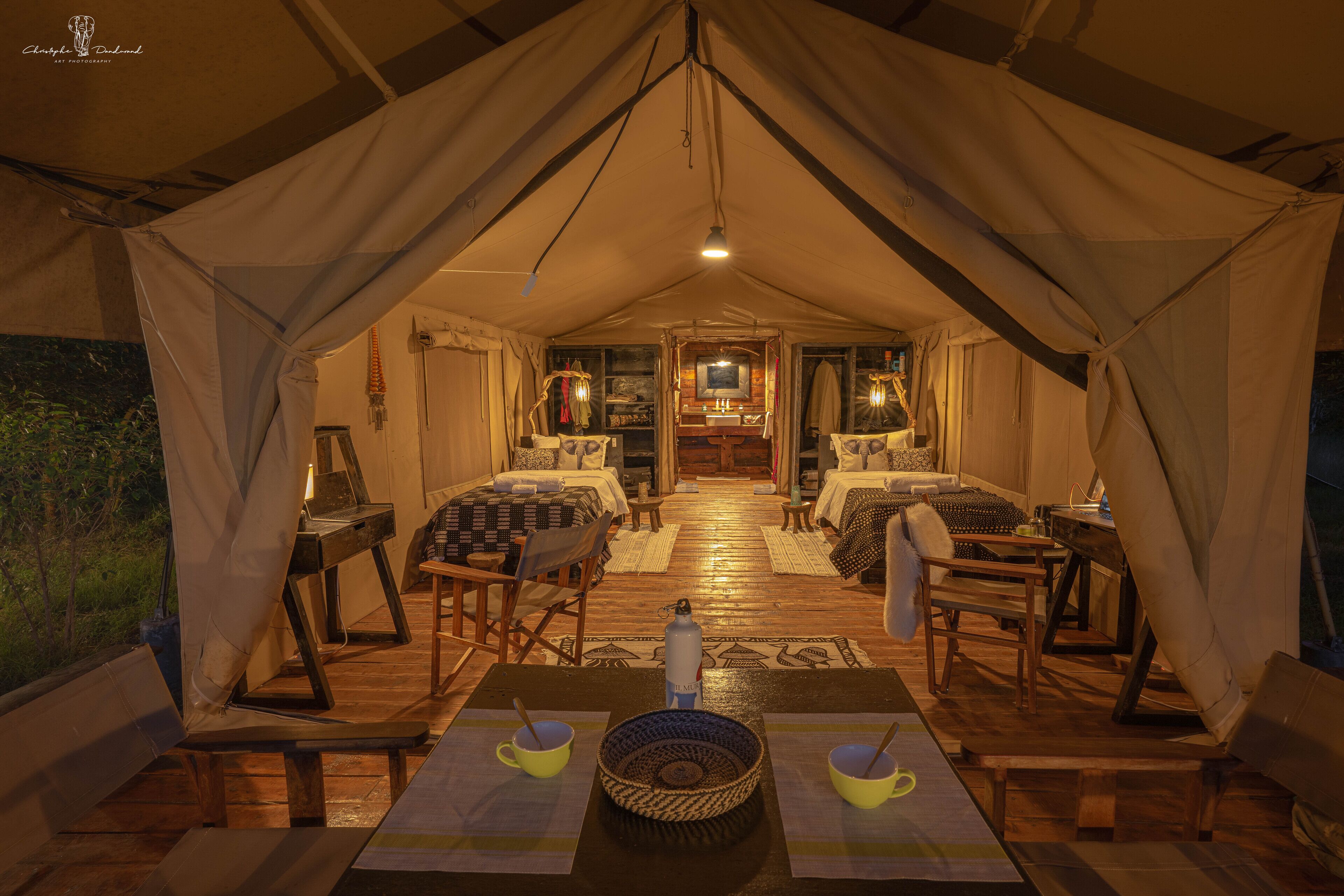 A cozy tented accommodation with two bedrooms, a central living area, and a dining space.