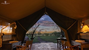 Una carpa con vistas a un atardecer, muebles de madera y una alfombra.
