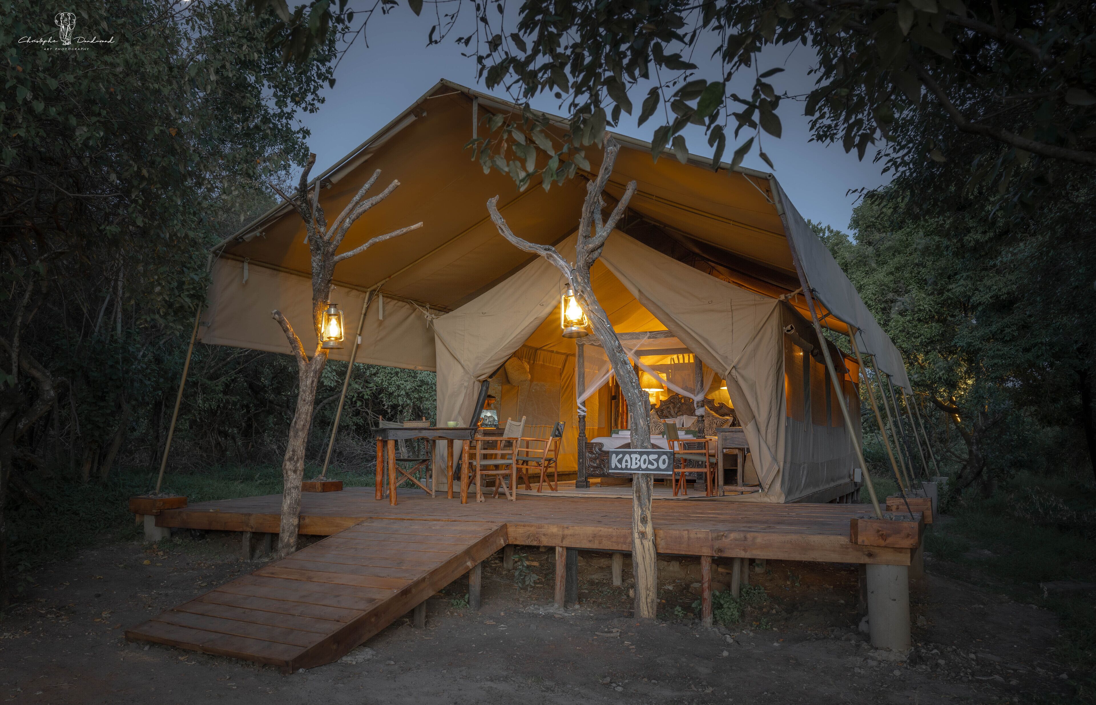 A tented accommodation with a wooden deck, a dining area, and a sign reading "KABOSO".