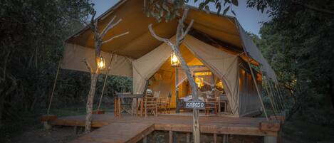 A tented accommodation with a wooden deck, a dining area, and a sign reading "KABOSO".