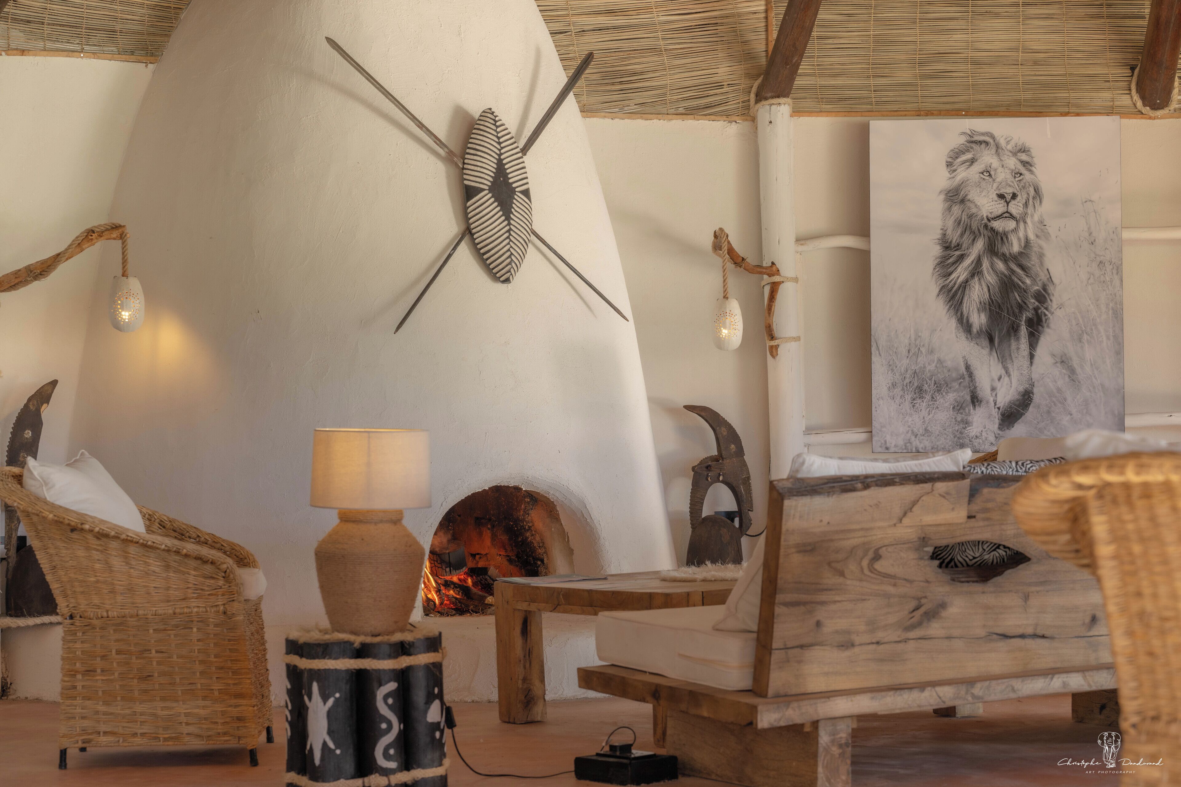 A cozy room with a fireplace, wicker furniture, and a lion painting.