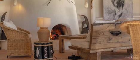 Una habitación acogedora con chimenea, mobiliario de mimbre y un cuadro de un león.