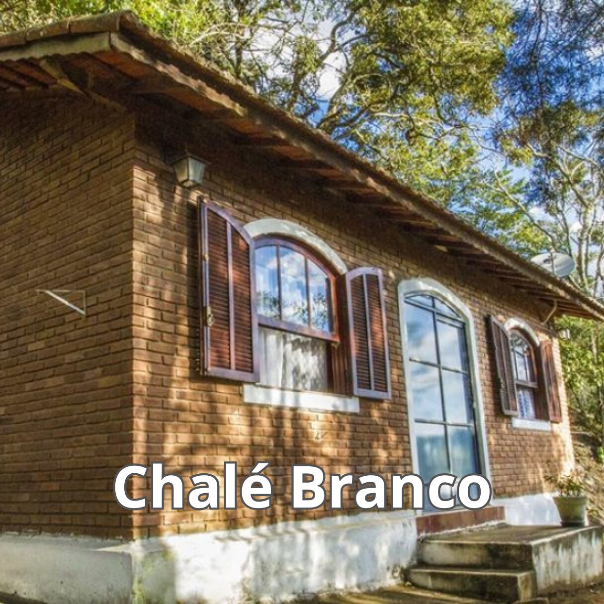 A brick building with arched windows and a door, labeled "Chalé Branco".