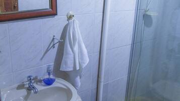 Un baño con lavabo, inodoro y cabina de ducha de vidrio.