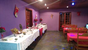 A dining area with tables set for a meal, purple walls, and wooden doors. - Pousada Céu de Luz - Próximo a Monte Verde (Itapeva)