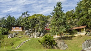 Una propiedad en una ladera con una escalera que lleva a una casa, rodeada de rocas grandes y árboles.