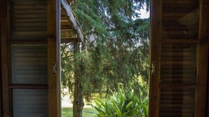 Una puerta de madera que da a un jardín con árboles y plantas.