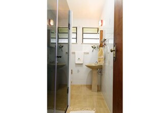 A bathroom with a glass shower door, a sink, and a mirror.