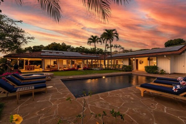 Une maison moderne dotée d’une piscine, de chaises longues et d’un espace patio.