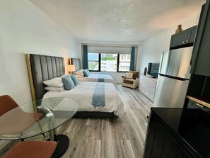 Une chambre d’hôtel équipée d’un lit, d’une table en verre, d’un canapé, d’une télévision et d’un réfrigérateur.
