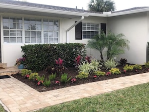 A house with a well-maintained garden, a paved walkway, and a large window with blinds. - Closest private rental home to beach access and JW Marriott! 3 minute walk! (Marco Island)