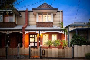 Stunning two-story home with a gabled roof and central dormer window, set amidst a quiet residential area.