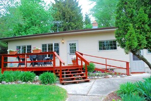 A house with a red staircase leading to a porch with outdoor furniture. - Cozy Cottage near Schwarz Supper Club, Road America, and Whistling Straights!! (New Holstein)