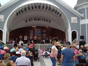 A covered outdoor stage with a band performing, surrounded by seated audience. - Spectacular Views From Beachfront Condo (Hampton)