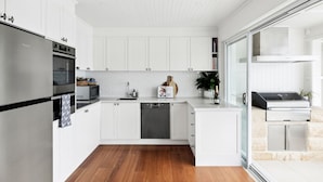 Una cocina moderna con armarios blancos, horno empotrado y lavavajillas.