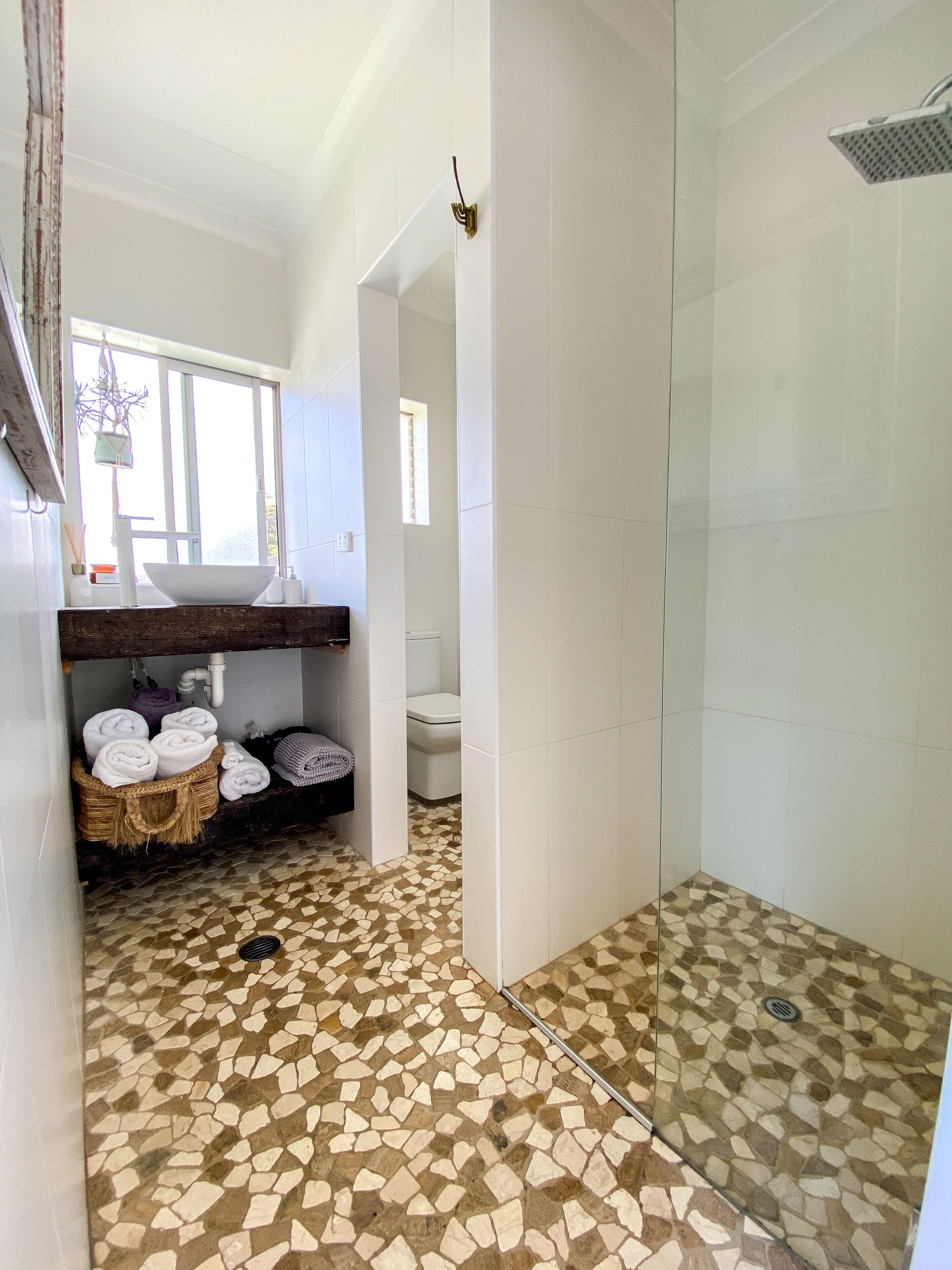 Une salle de bain avec un sol en mosaïque, une douche en verre et un lavabo avec un receveur blanc.