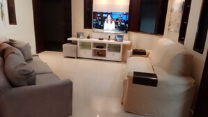 A living room with a grey sofa, a beige sofa, and a white entertainment unit with a flat-screen TV. - 5-bedroom house in condominium, comfort, air conditioning, 55" SmartTV, Wi-Fi, pool, lagoon, beach. (Vilas do Atlântico)