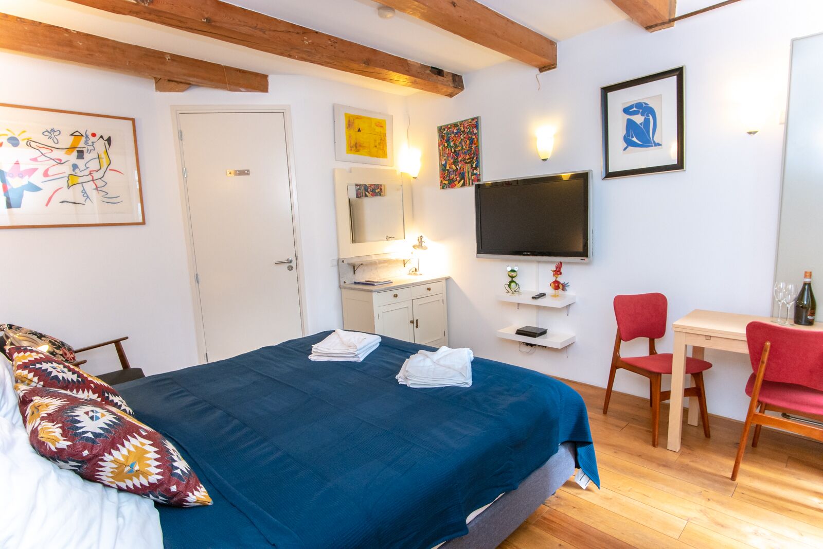 A hotel room with a bed, a desk, a TV, and a chair.
