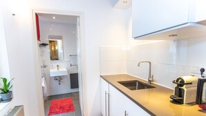 A compact kitchen with a sink, a coffee machine, and a red rug.