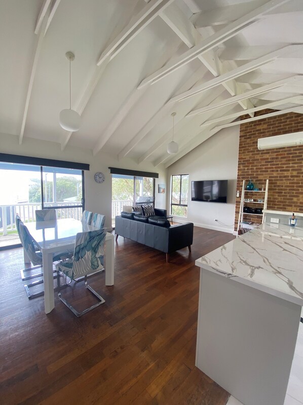 A spacious living area with a dining table, sofa, and a kitchen island.
