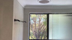 Une salle de bain avec une fenêtre, un porte-serviettes et une plante.