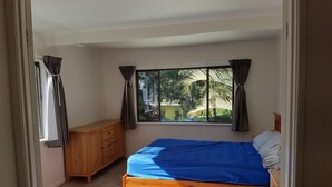 A bedroom with a bed, wooden dresser, and a window with curtains. - Lil's Place - Happy Valley - K'gari (Fraser Island) (Fraser Island)