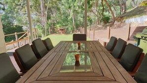 A wooden table with six chairs, surrounded by a wooden deck with a glass top. - Lil's Place - Happy Valley - K'gari (Fraser Island) (Fraser Island)
