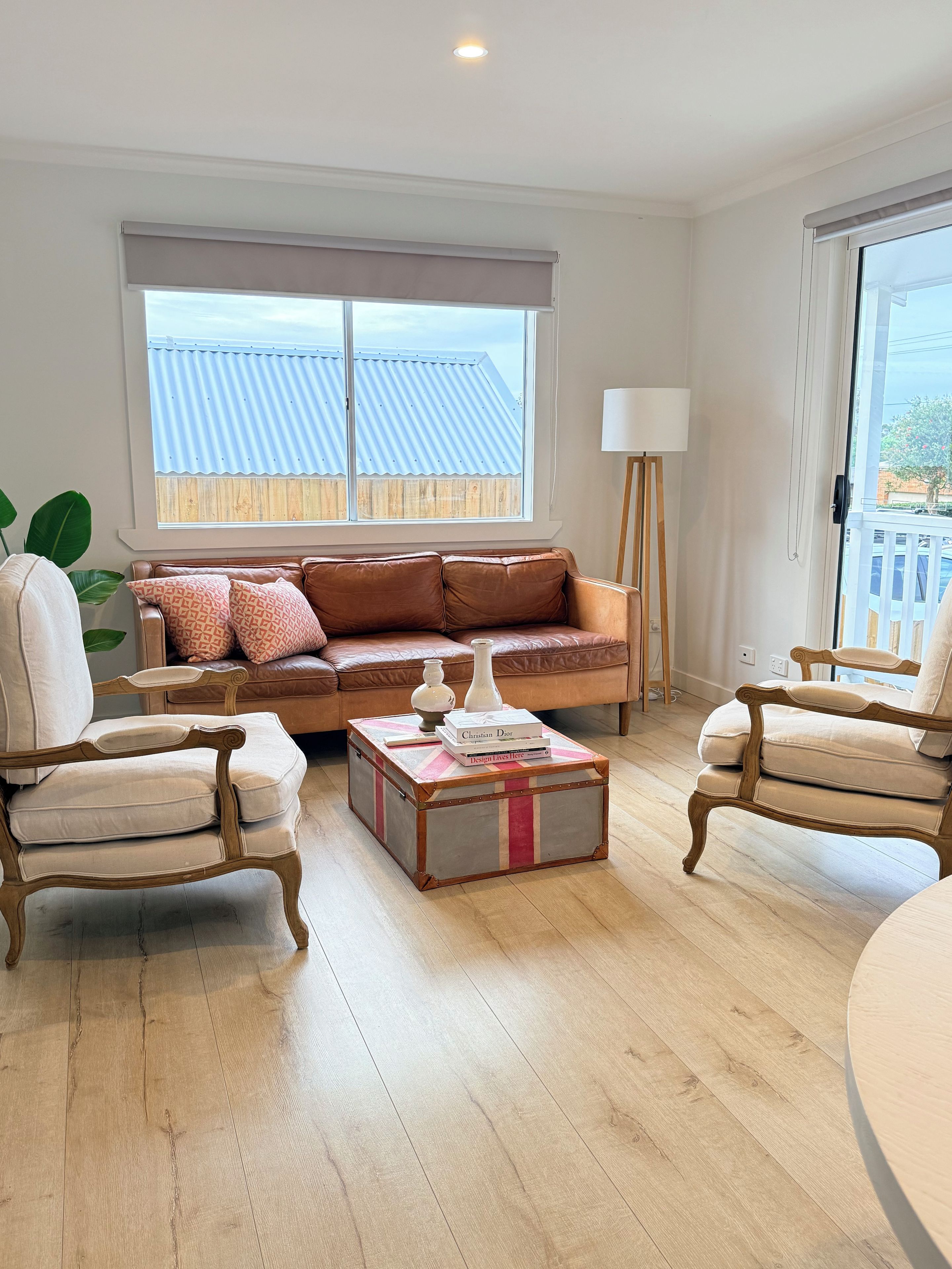 A living room with a sofa, two armchairs, a coffee table, and a window with blinds.