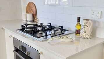 A kitchen with white cabinets, a stove, an oven, and a countertop with a bottle and a decorative plate.