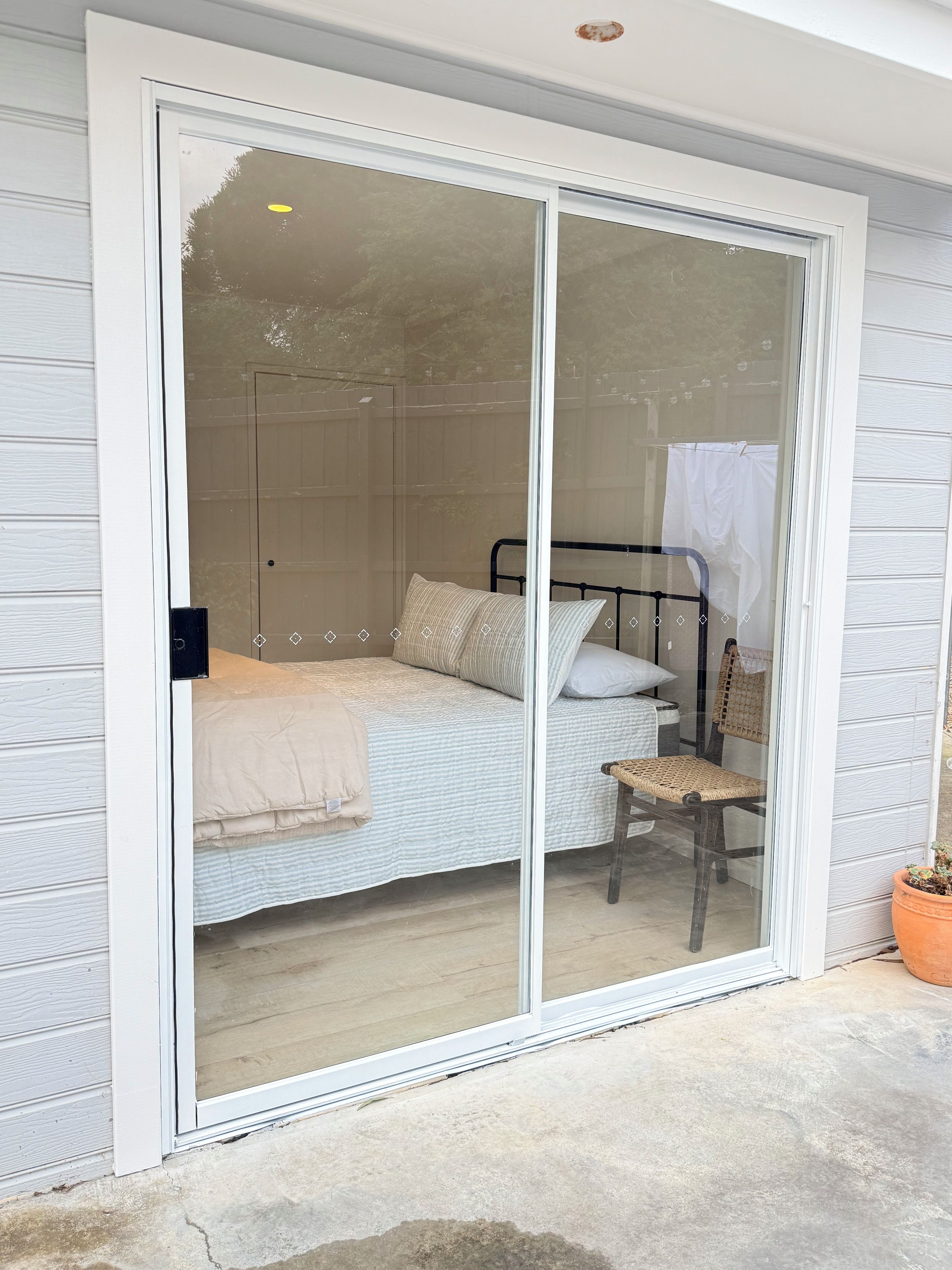 A room with a bed, a chair, and a sliding glass door leading to an outdoor area.