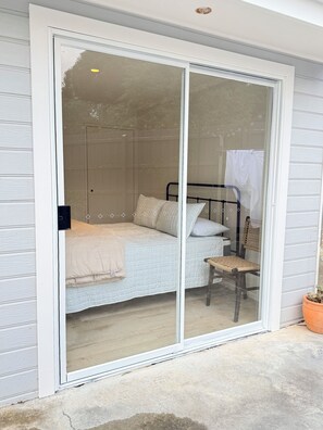 A room with a bed, a chair, and a sliding glass door leading to an outdoor area. - Miss McCrae walk to everything!!!! (McCrae)