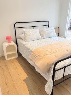 A bed with a striped bedding, a white pillow, and a beige throw. - Miss McCrae walk to everything!!!! (McCrae)